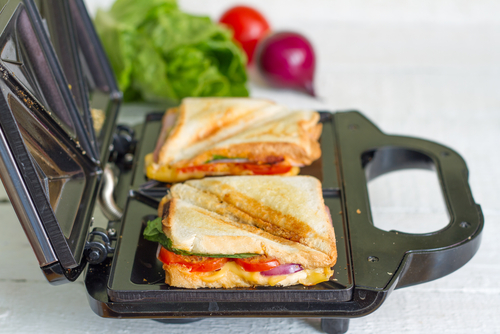 Appareil à croque-monsieur de profil avec des croque-monsieur sur ses plaques